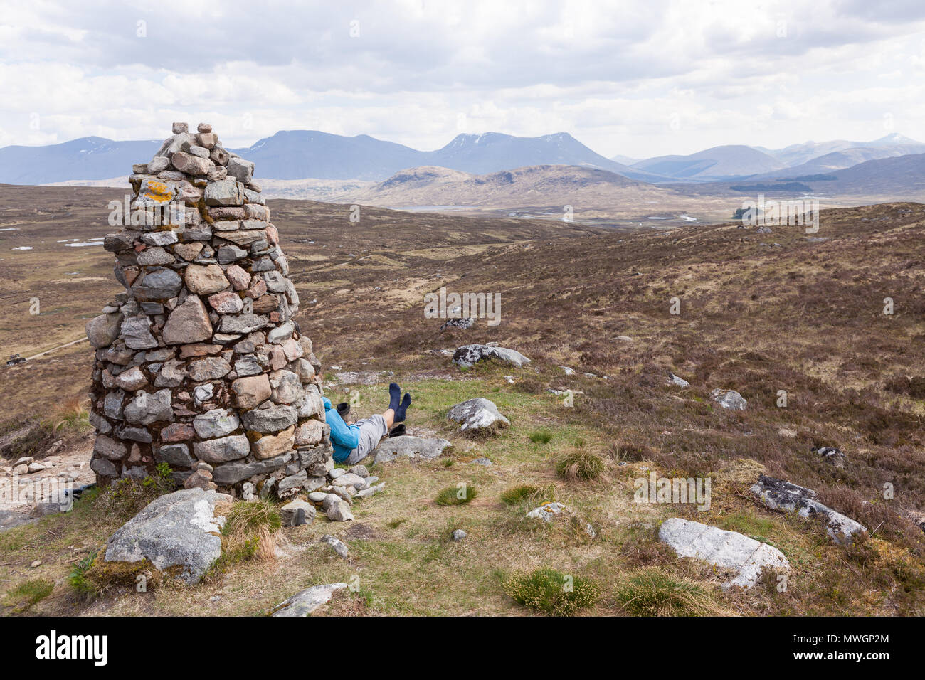 Man resting by the Fleming Cairn on Rannoch Moor, West Highland Way, Scotland. Stock Photo