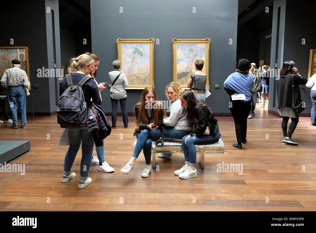 Young women sitting on bench talking & people visiting the Musée d'Orsay  art gallery & Monet The Woman with a Parasol 1886 Paris France KATHY DEWITT  Stock Photo - Alamy
