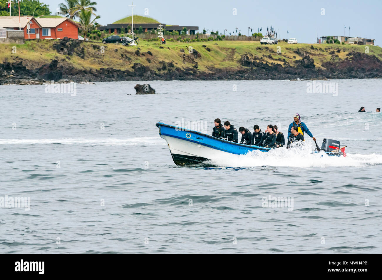 Small open boat with outboard motor bringing back divers in wetsuits after a dive, Hanga Roa, Easter Island, Rapa Nui, Chile Stock Photo