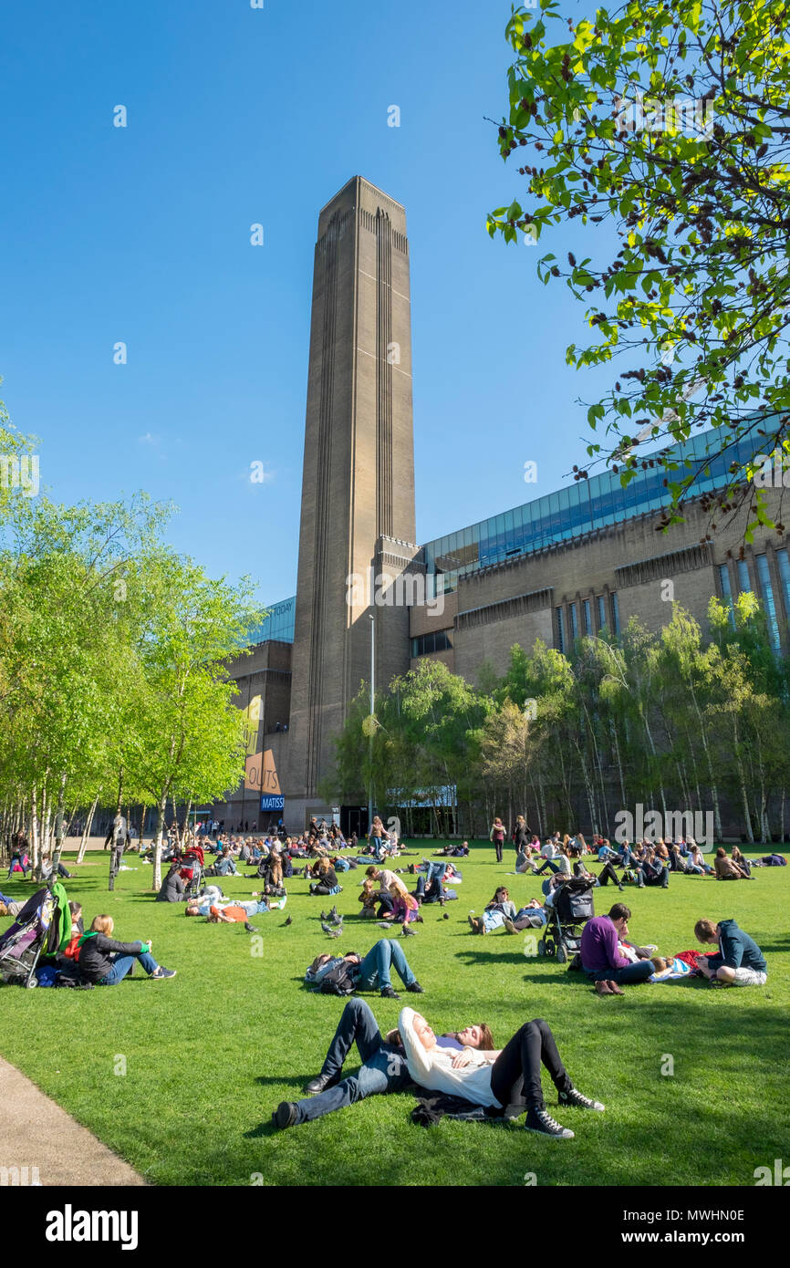 View of people on grass outside  the Tate Modern museum on Southbank, London, England, UK Stock Photo
