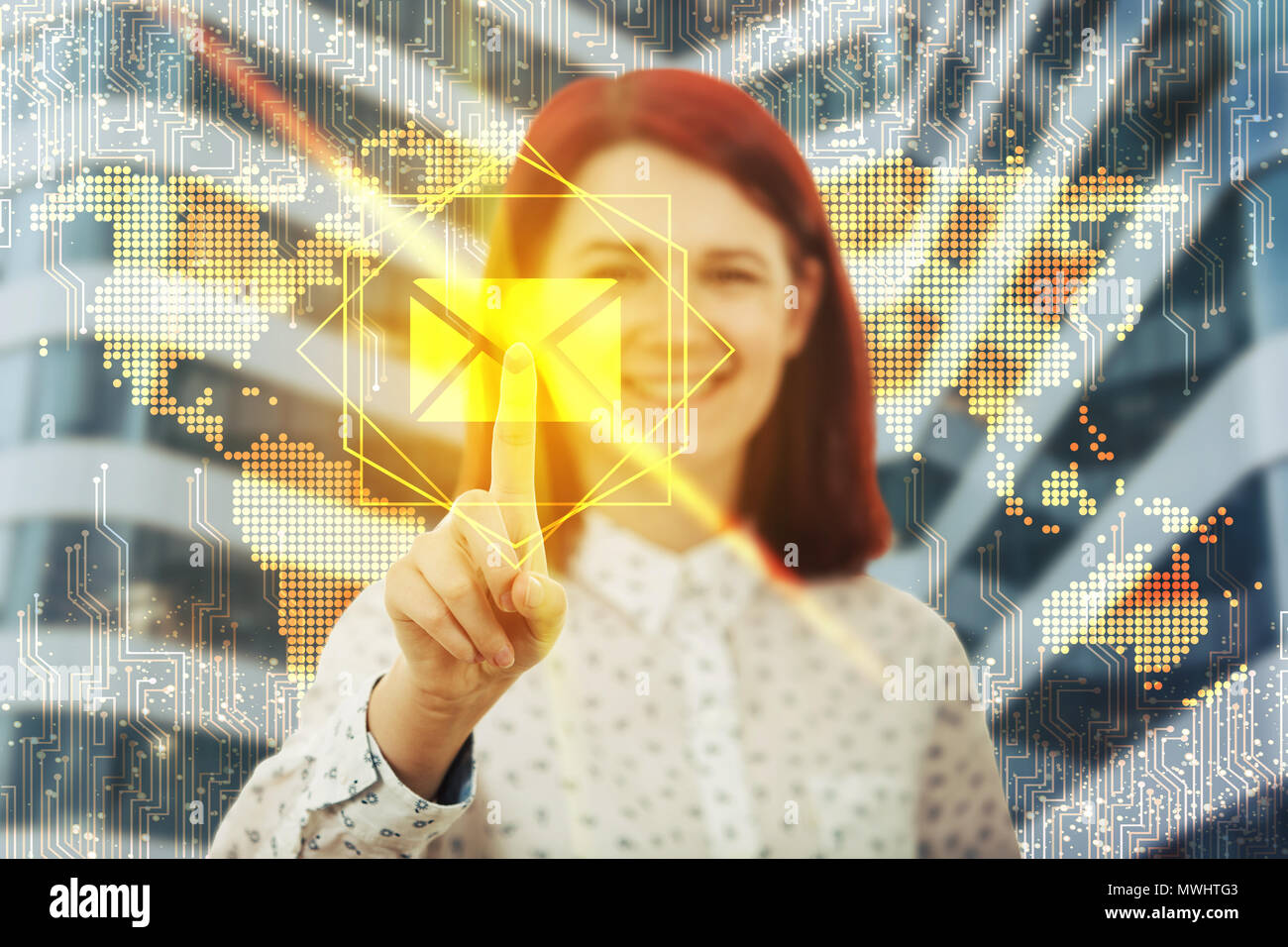 Smiling woman touching digital screen interface. Press on the golden envelope message icon over world map hologram background. Modern technology conce Stock Photo