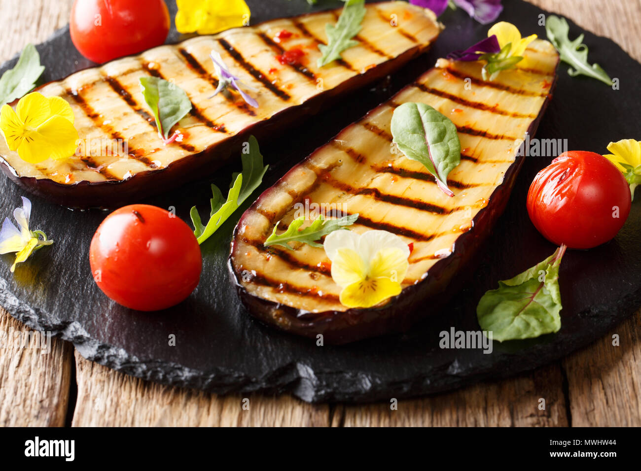 Summer appetizer from grilled eggplants and tomatoes with herbs and