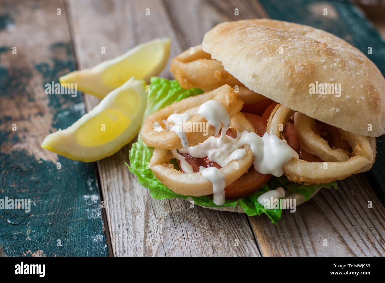 deep fried calamari rings on bun with tomato salad Stock Photo