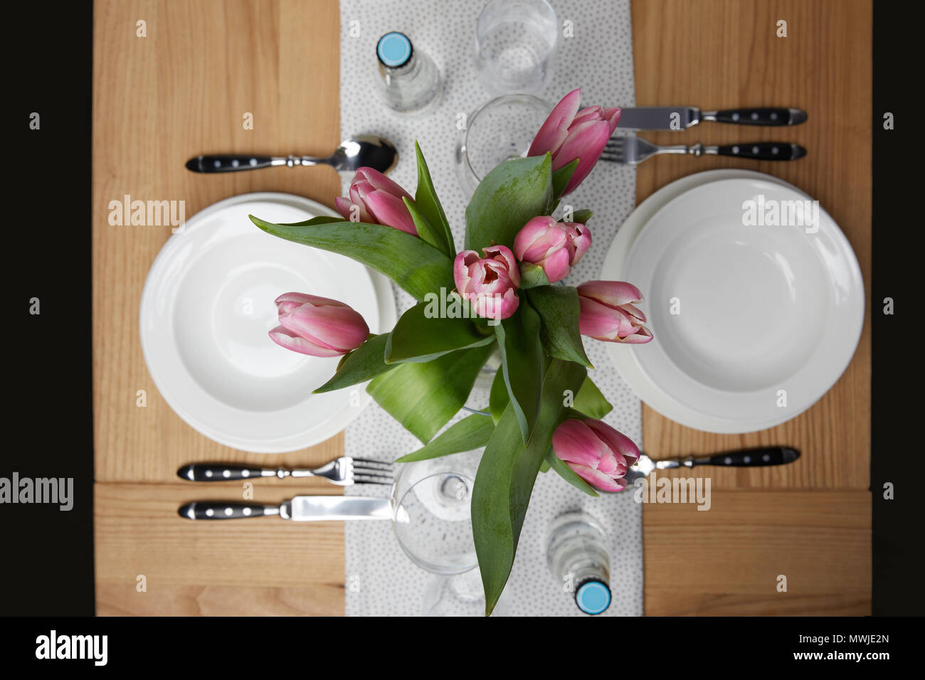 Dinnerware with plates on table with flowers in vase Stock Photo