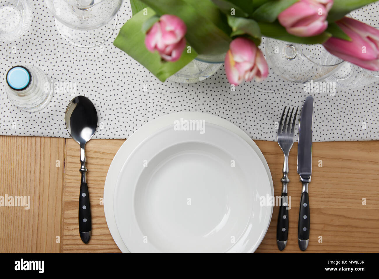 Dinnerware with plates on table with flowers in vase Stock Photo