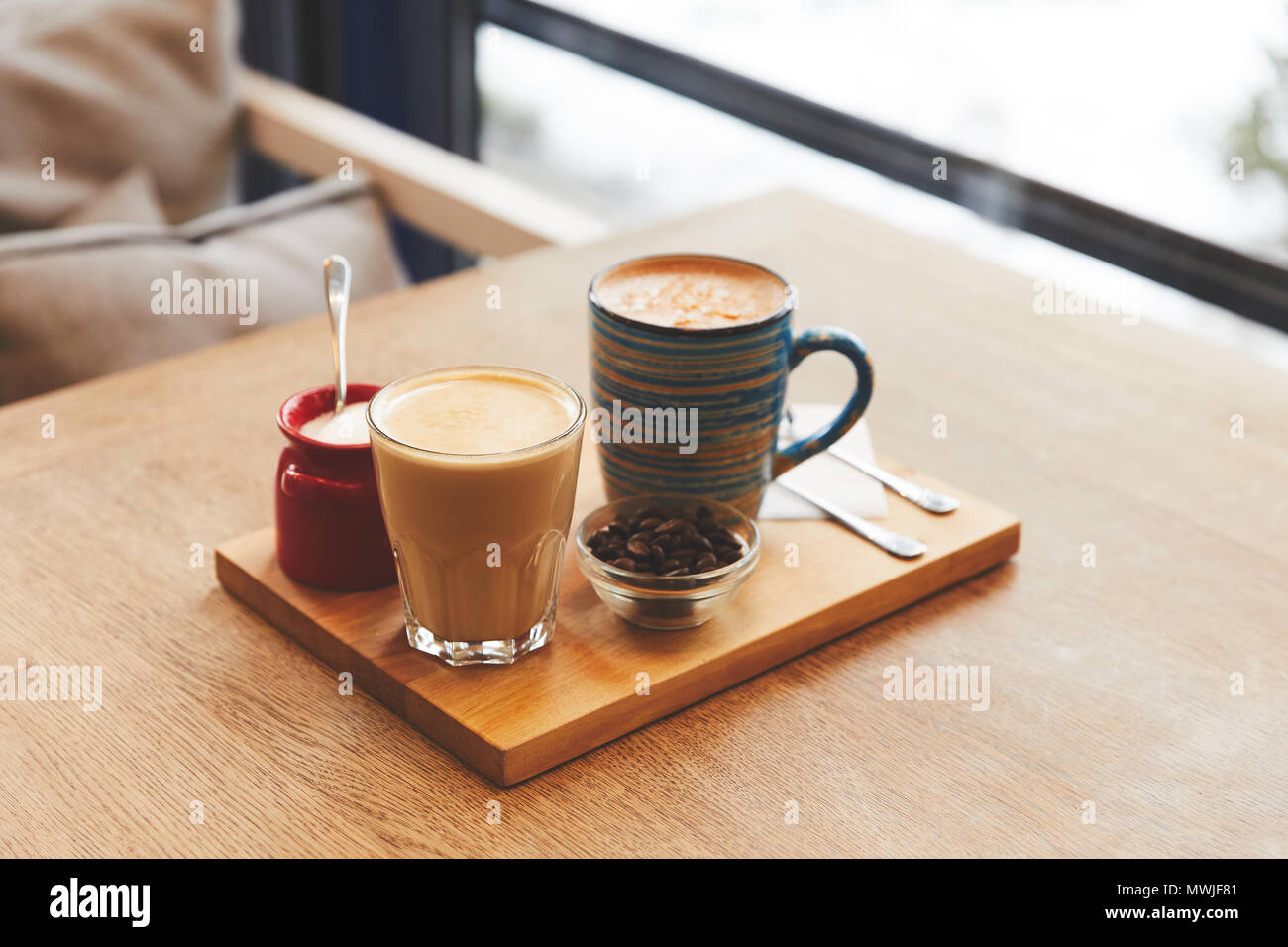 Coffee drinks with beans and orange peel on table in cafe Stock Photo