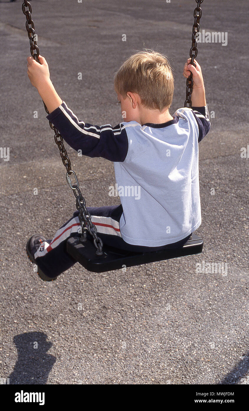 Six year old boy on a swing (rear view) Stock Photo