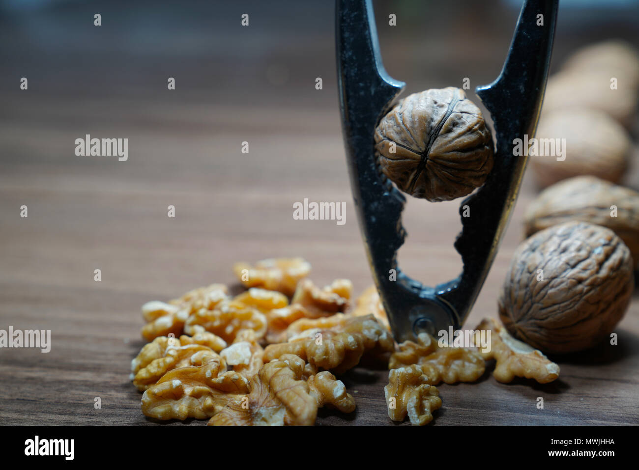 Whole walnuts, kernel walnuts and nutcracker on dark walnut table background Stock Photo