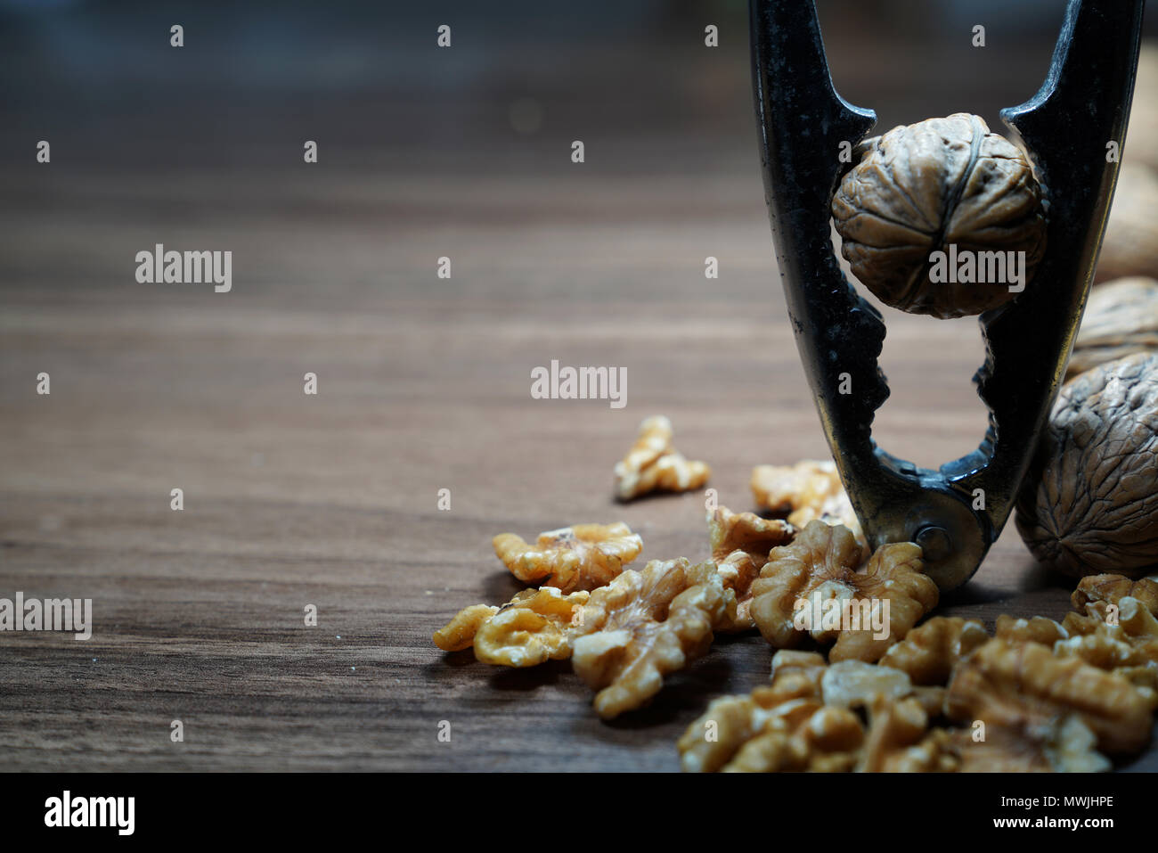 Whole walnuts, kernel walnuts and nutcracker on dark walnut table background Stock Photo