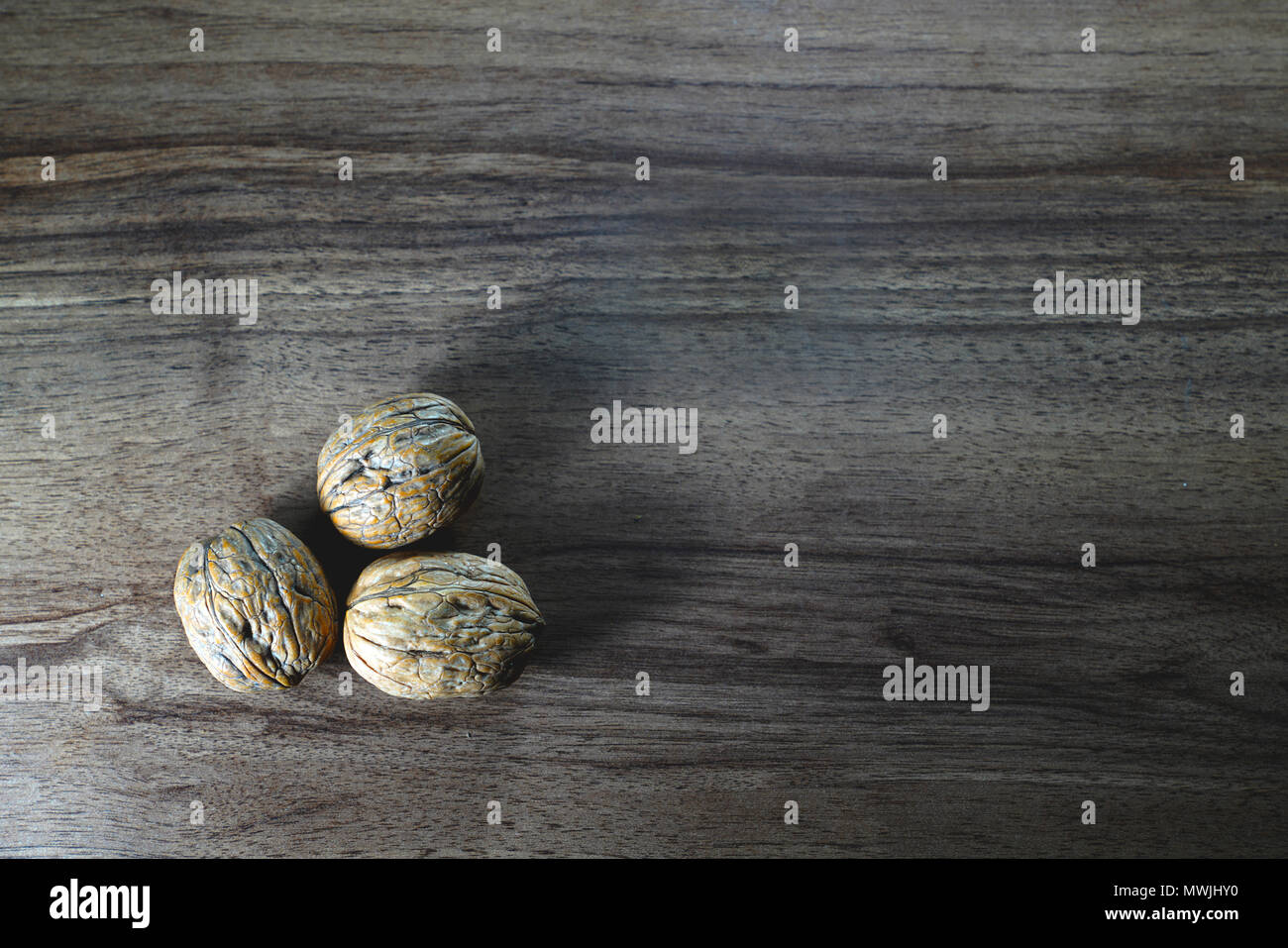 Top view of three walnuts on dark walnut table background Stock Photo