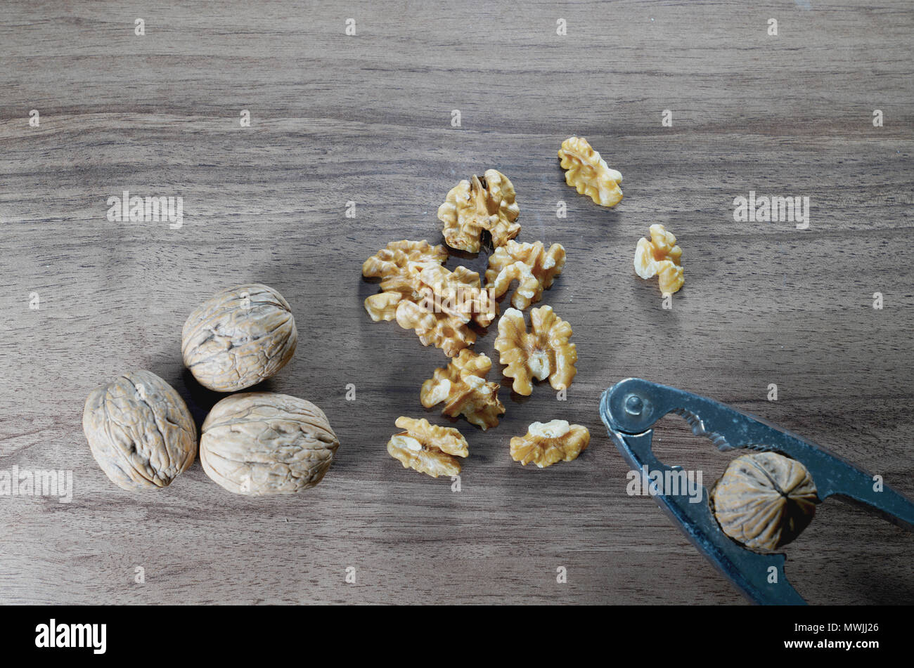 Top view of whole walnuts, kernel walnuts and nutcracker on dark walnut table background Stock Photo