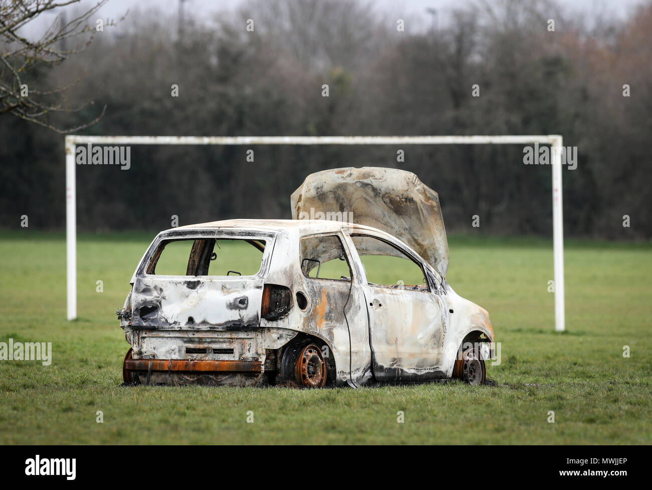 Burned Out stolen car abandoned on a community football pitch next to a council estate in Hampshire Stock Photo