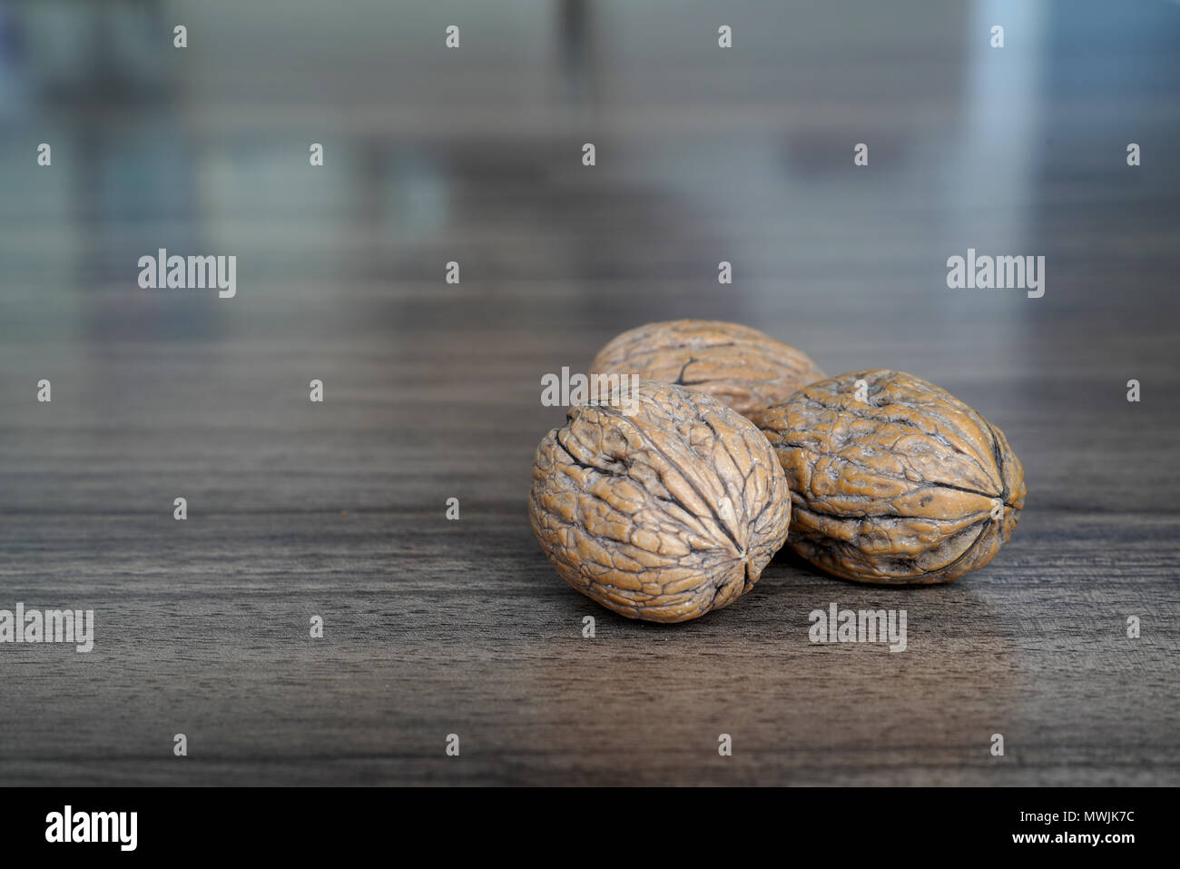 Three walnuts on dark walnut table background Stock Photo