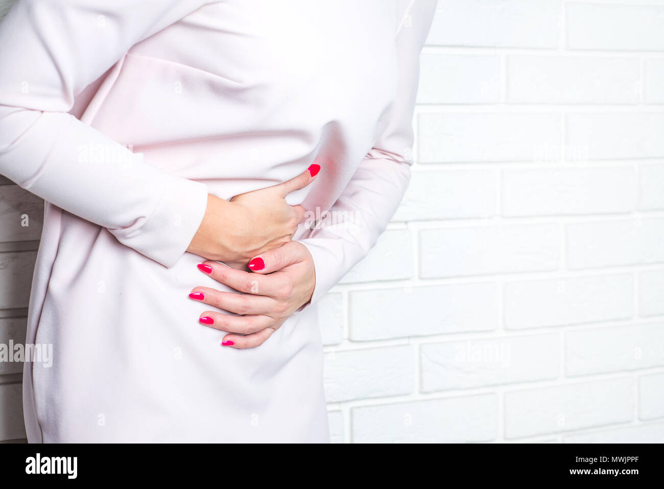 Abdominal pain, stomach ache. The woman is holding her belly, it hurts