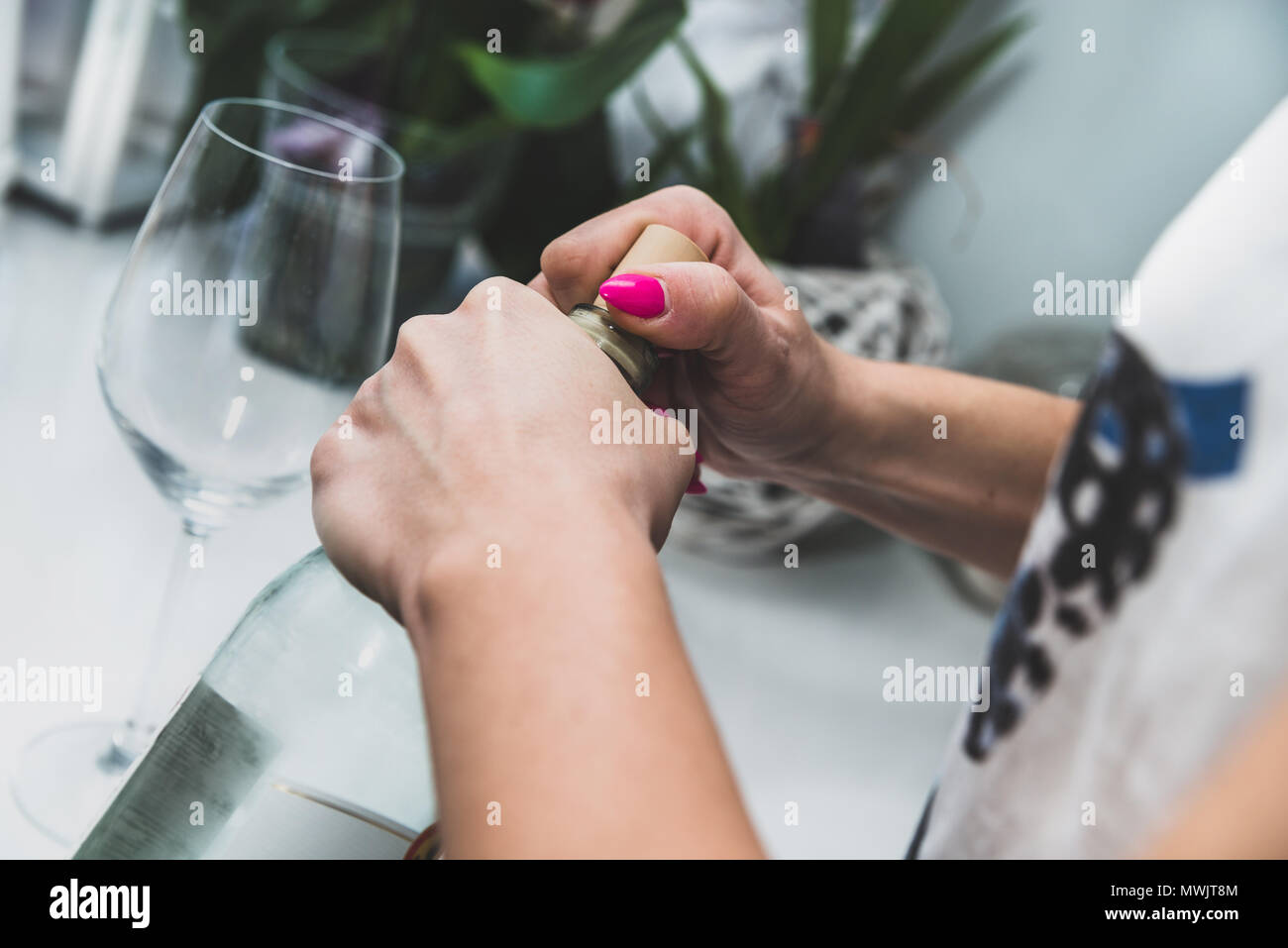 The woman is trying to open a bottle with wine, alcohol. Longing for alcohol, for wine. Alcohol problems concept. Drinking wine, party, fun, lonelines Stock Photo