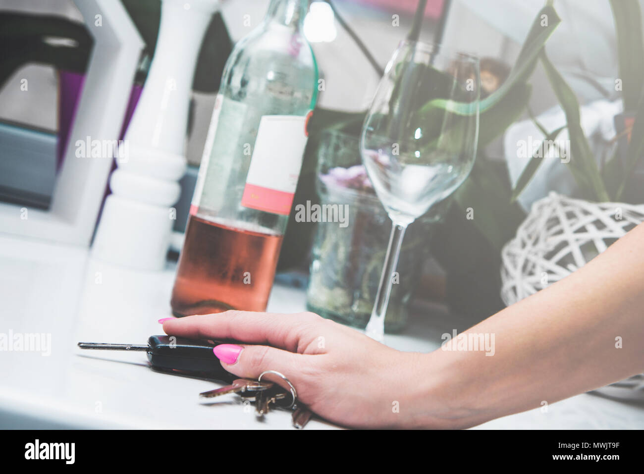 Alcohol and drinking alcohol and driving a car. I drink, I'm not driving. Irresponsibility, lack of reason. Woman holds car keys with hand, in the bac Stock Photo
