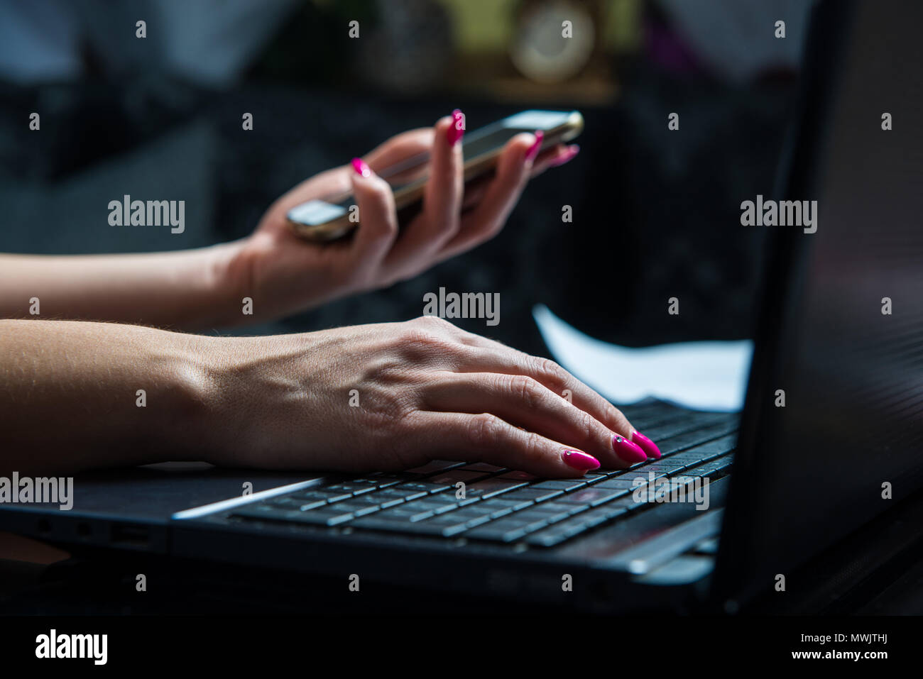 Transactions on your mobile phone and laptop. The woman checks the bank code, information needed to use the laptop. Online shopping, bank transfers, b Stock Photo