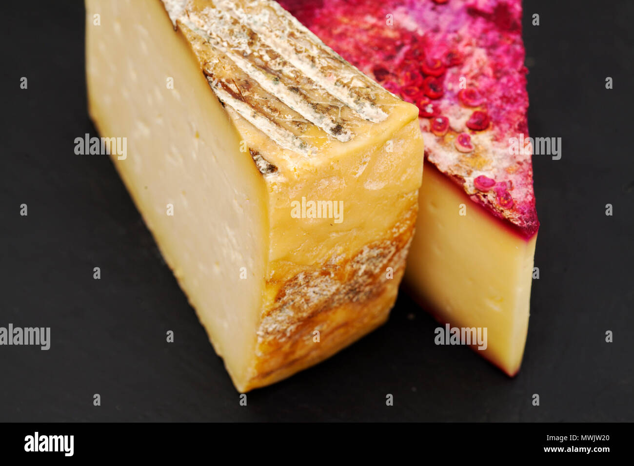 wedges of hard sheep milk cheese from Gran Canaria,  one dyed with opuntia cactus fruit on the outside Stock Photo