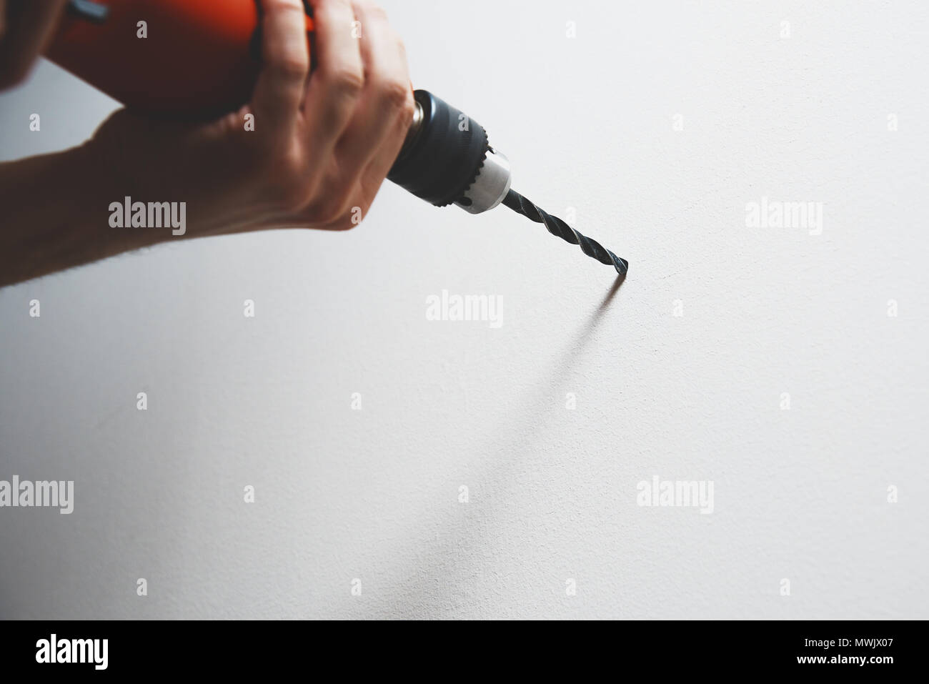 Drilling in the wall. The man is holding a screwdriver or drill in hand