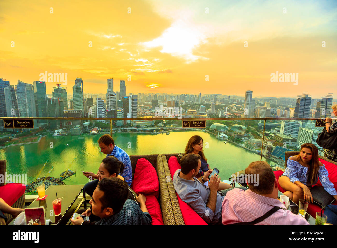 Singapore - May 3, 2018: lifestyle people enjoy sunset and panoramic views from rooftop SkyBar CE THE VI on 57th floor of Marina Bay Sands hotel and casino. Financial district skyline on background. Stock Photo