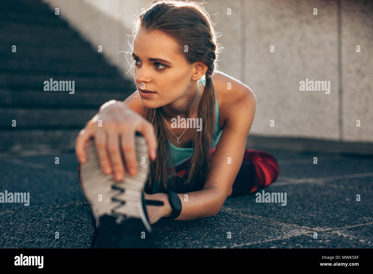 Healthy young woman exercising outdoors. Fit young woman doing stretching workout in morning. Stock Photo