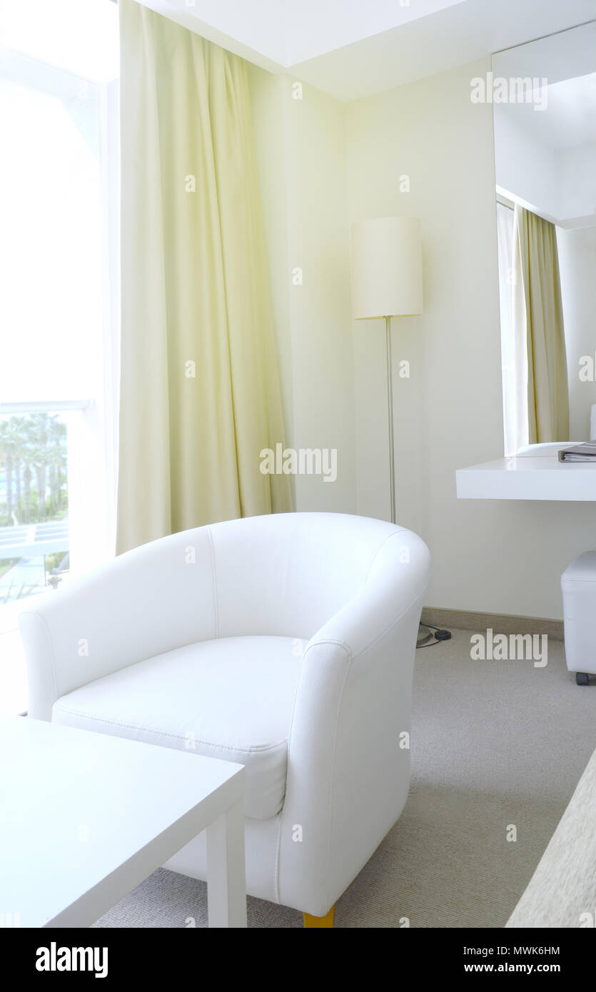 Fragment of the room in the hotel. A table, armchair and floor lamp in the corner of the hotel room Stock Photo