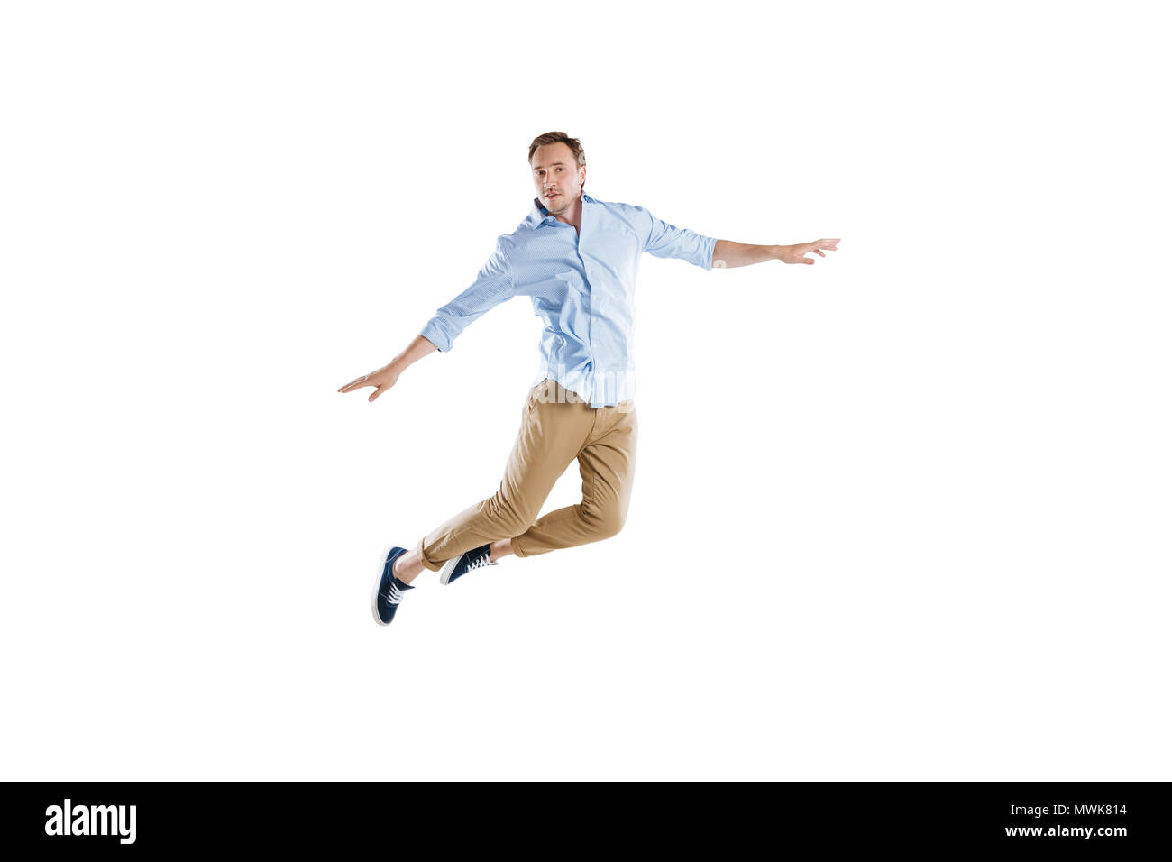 young casual man jumping with arms outstretched isolated on white Stock Photo