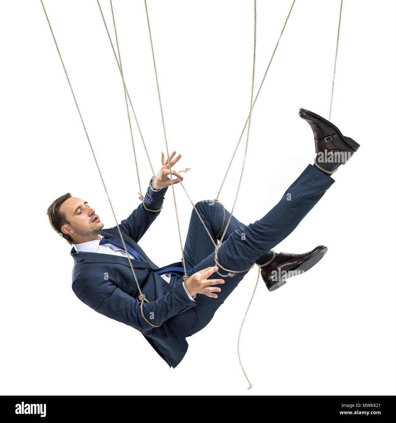 businessman trying to break free while hanging on manipulating ropes isolated on white Stock Photo