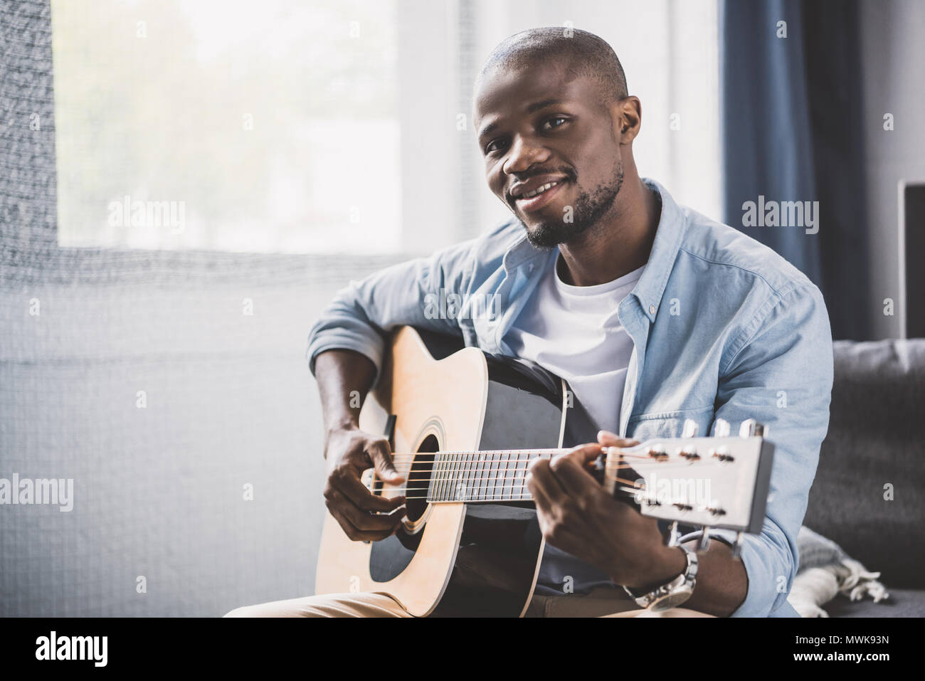African american man playing acoustic guitar at home Stock Photo - Alamy