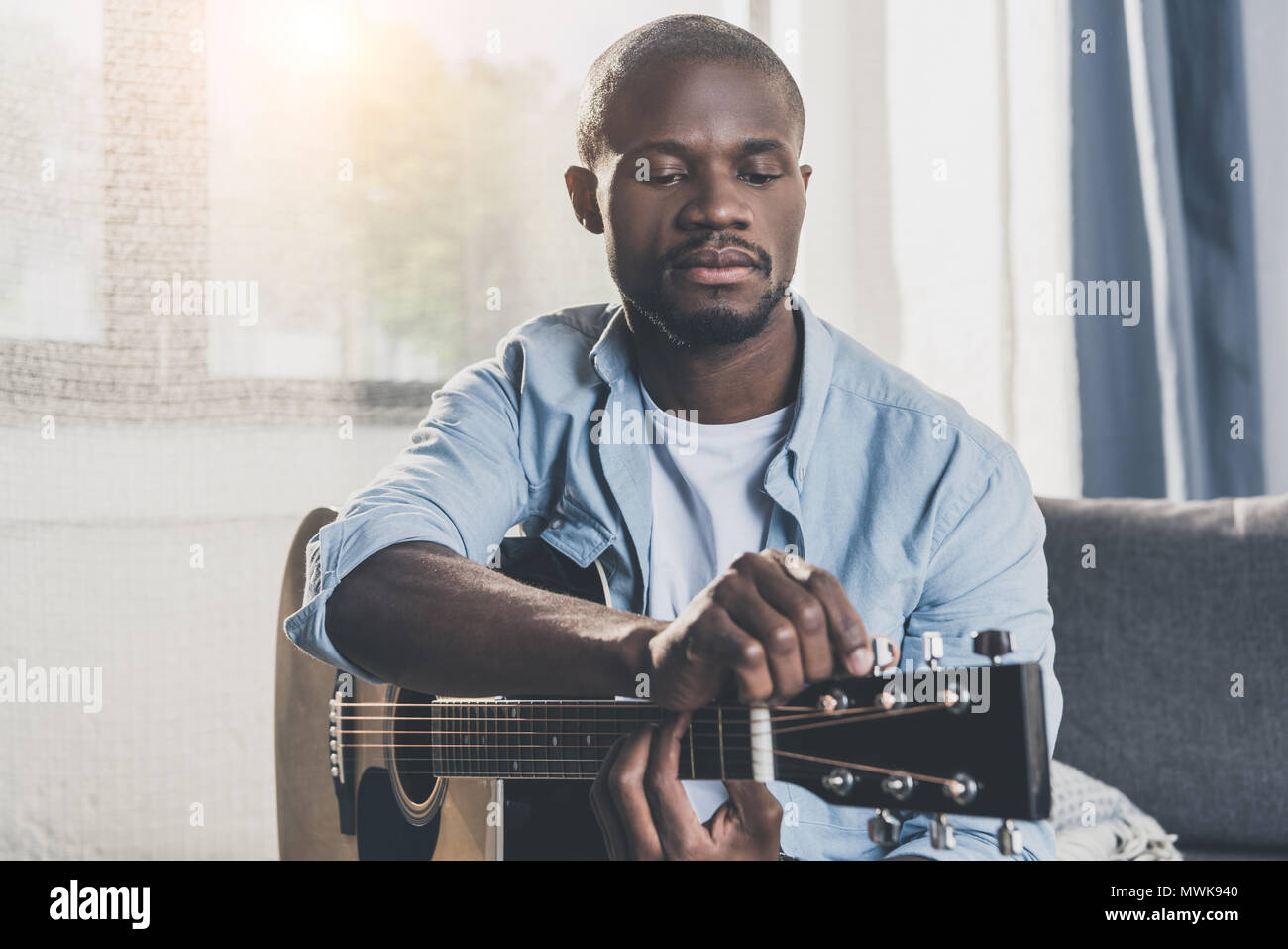 African american man tuning acoustic guitar at home Stock Photo - Alamy