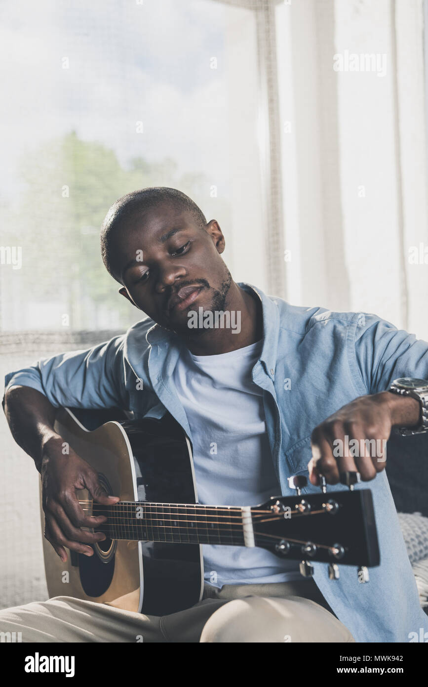 African american man tuning acoustic guitar at home Stock Photo - Alamy