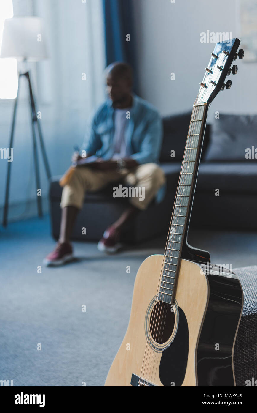 Closeup view acoustic guitar standing in room and African american
