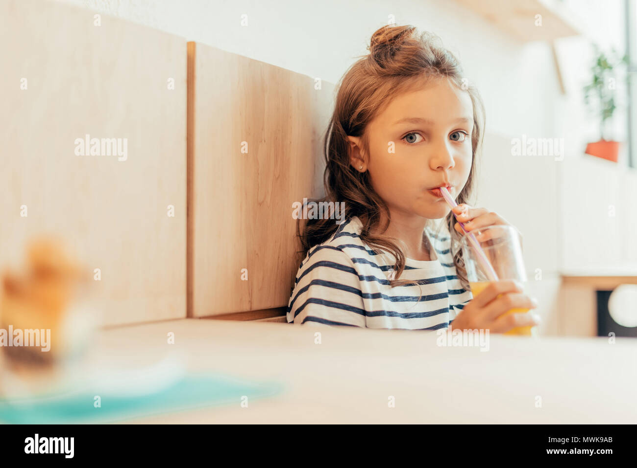cute little girl drinking orange juice while sitting in cafe Stock ...