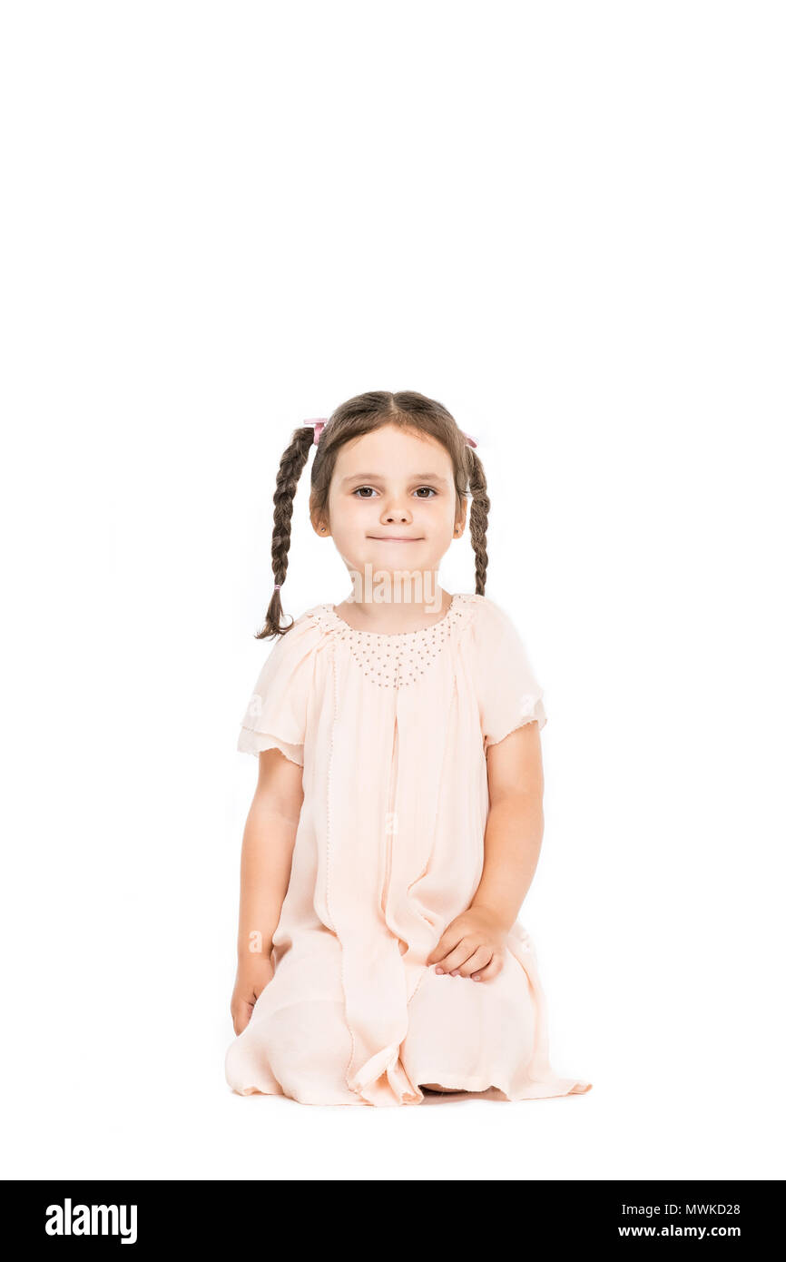 little adorable girl in beautiful dress with braids sitting and looking ...