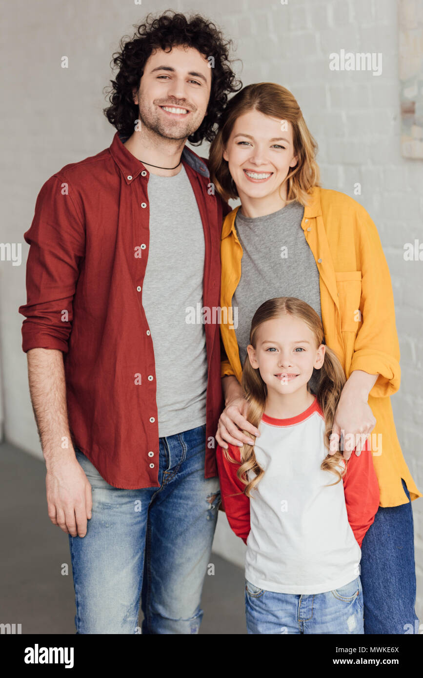 happy young family standing together and smiling at camera Stock Photo ...