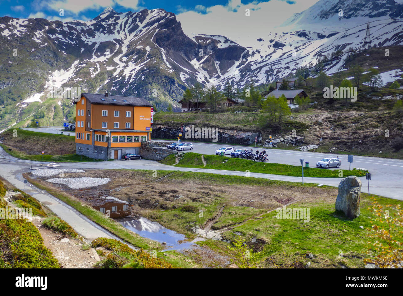 Orange hotel with parked cars and snowy weather in the mountains on the Simplon Pass, between Switzerland and Italy Stock Photo