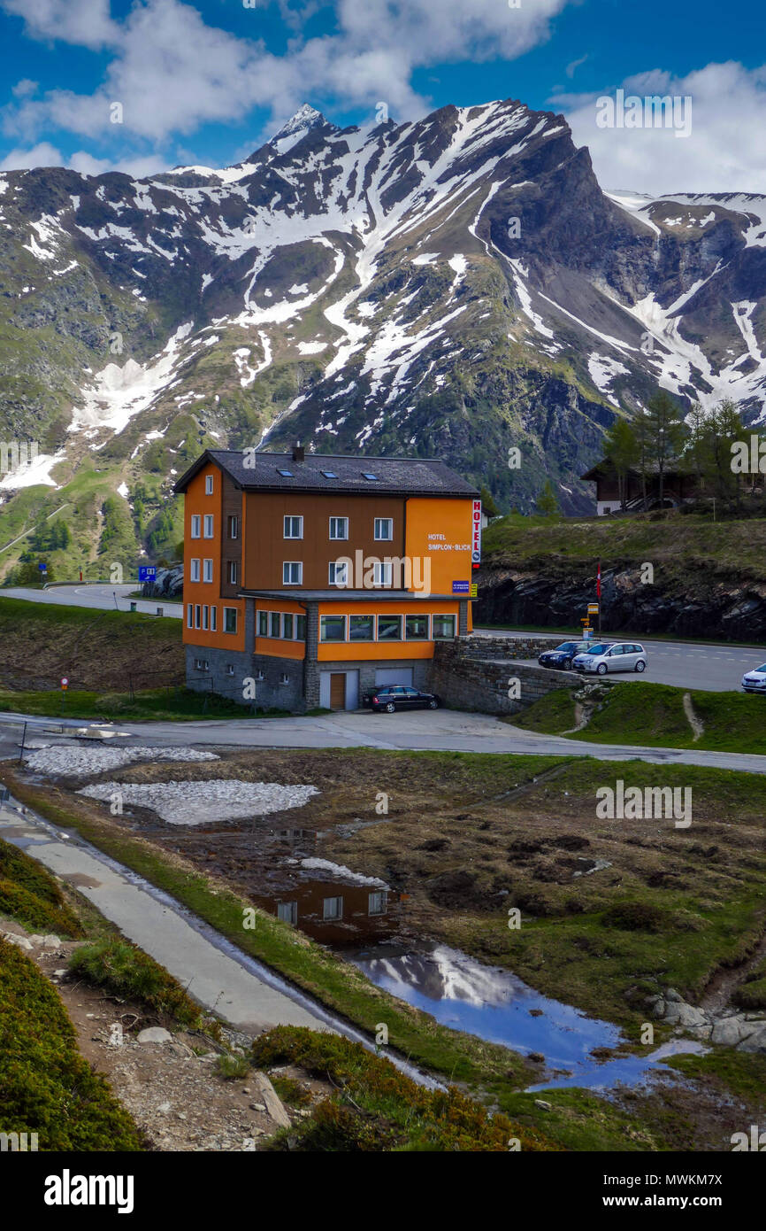 Orange hotel with parked cars and snowy weather in the mountains on the Simplon Pass, between Switzerland and Italy Stock Photo