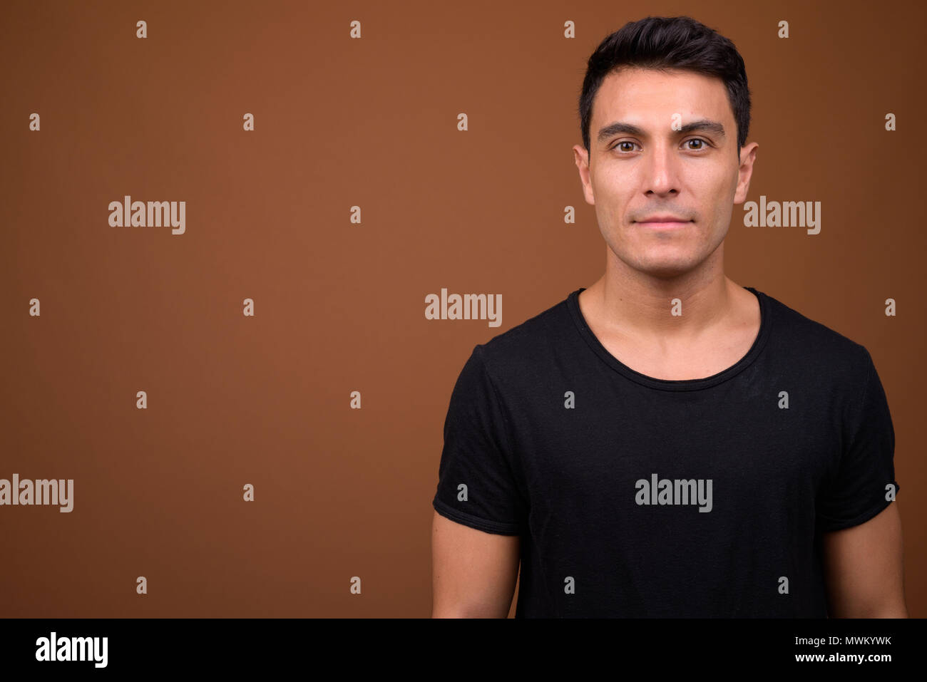 Young handsome Hispanic man against brown background Stock Photo