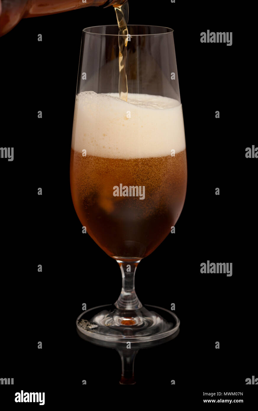 dark beer being poured into taster glass isolated on black Stock Photo