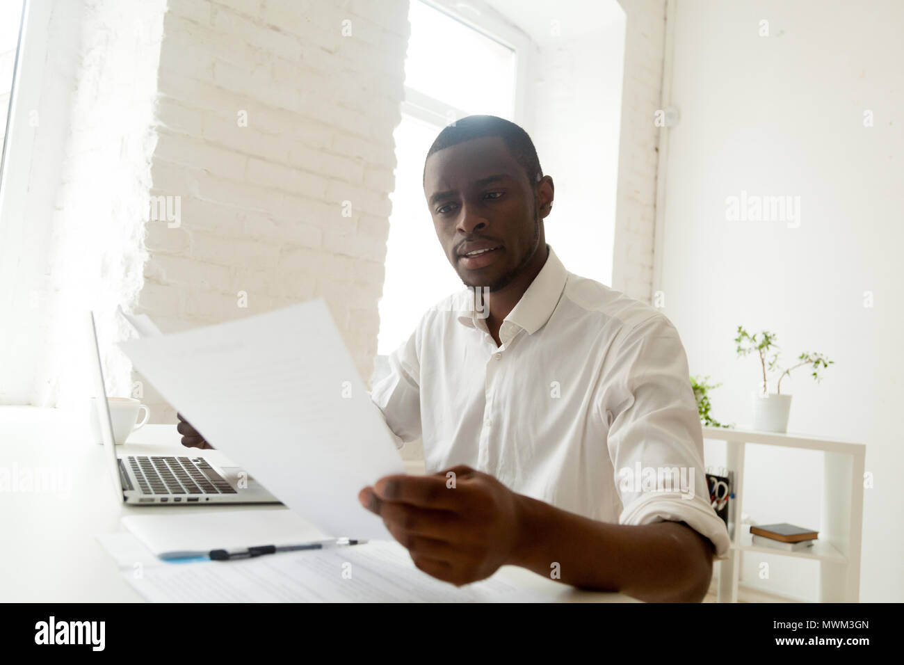 Focused black worker analyzing company statistics reading papers Stock Photo