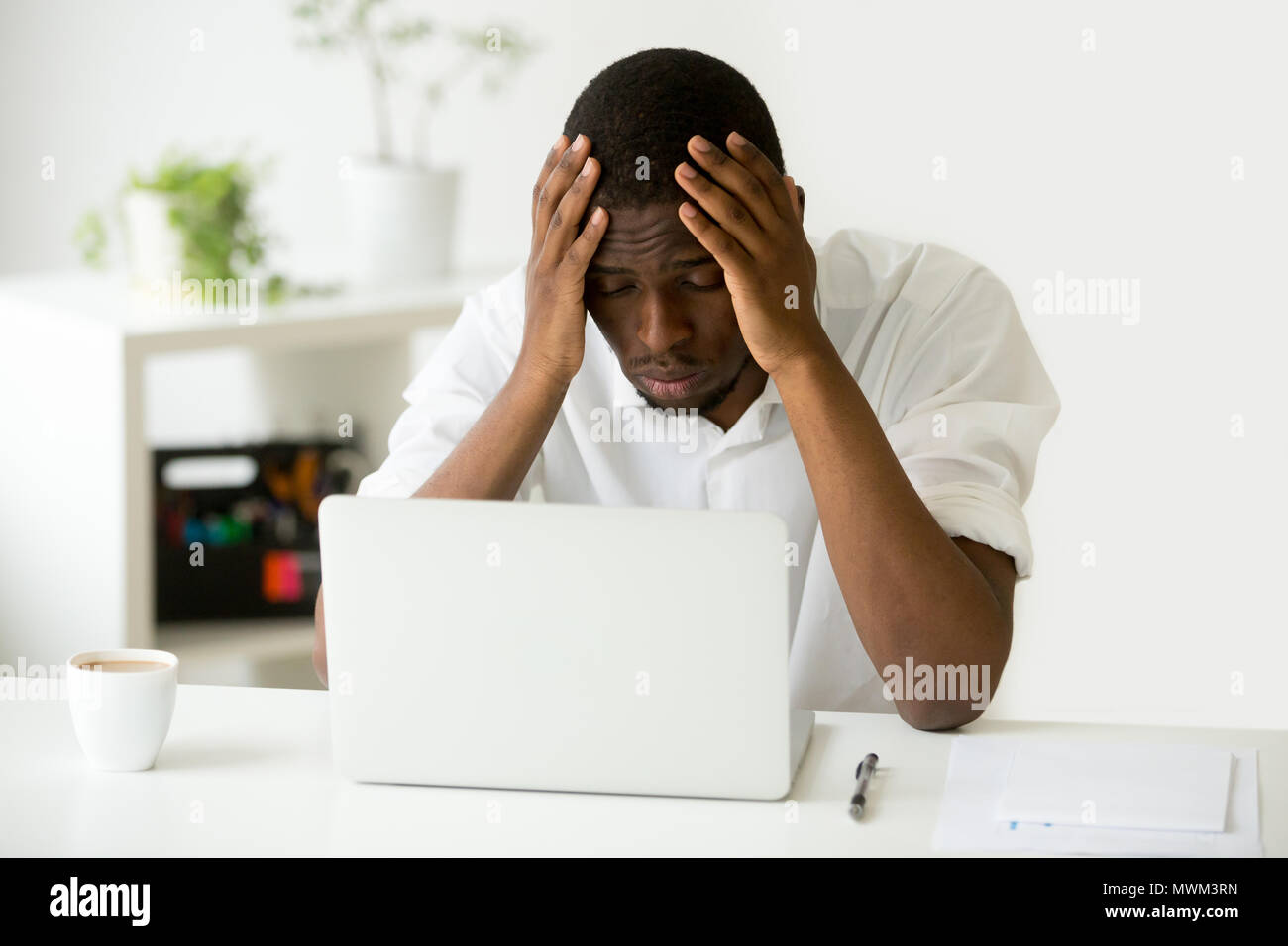 Depressed African American worker upset with company crisis Stock Photo