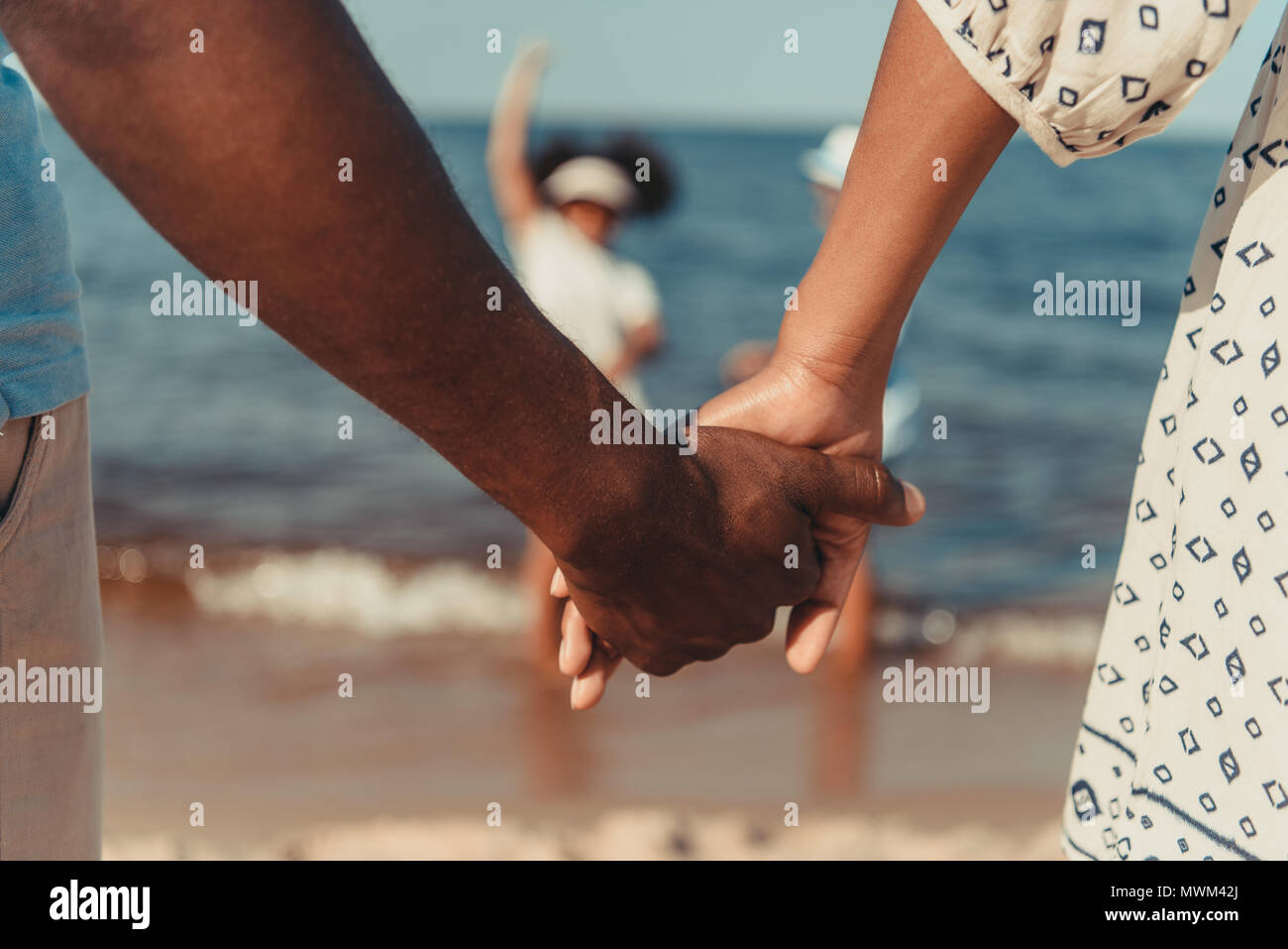 close-up partial view of african american couple holding hands while ...