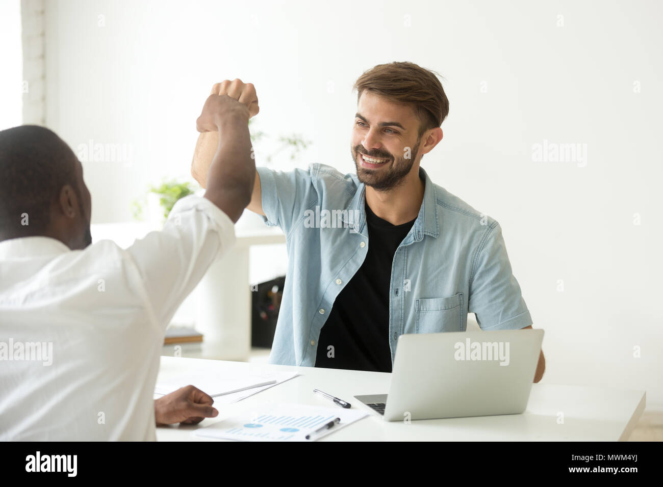 Colleagues giving fist bumps after reaching shared business goal Stock Photo