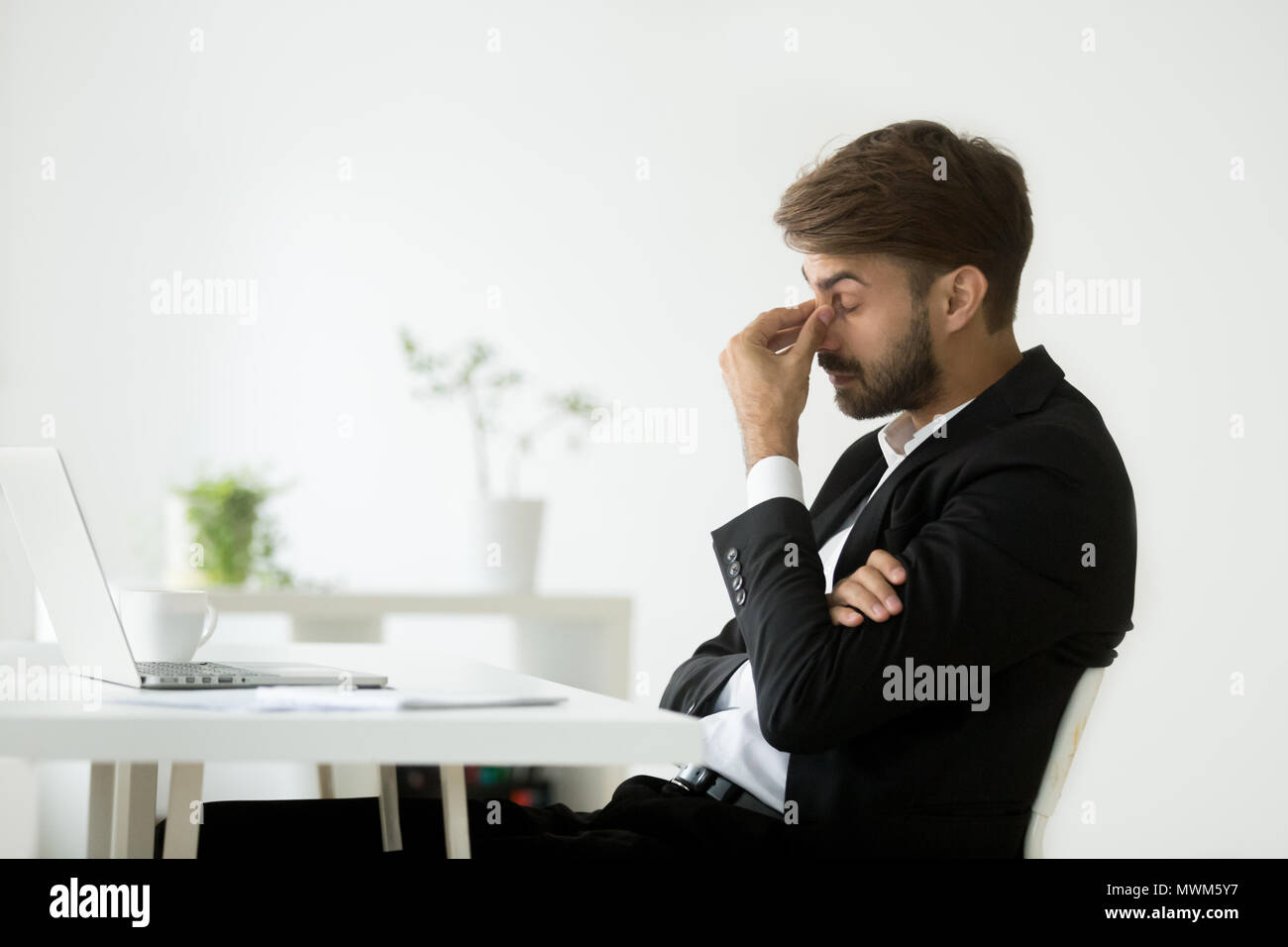 Exhausted businessman feeling tired massaging nose bridge Stock Photo