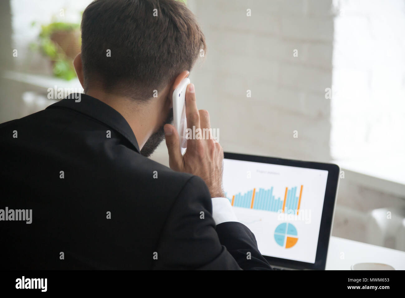 Businessman multitasking, talking on phone while working at lapt Stock Photo