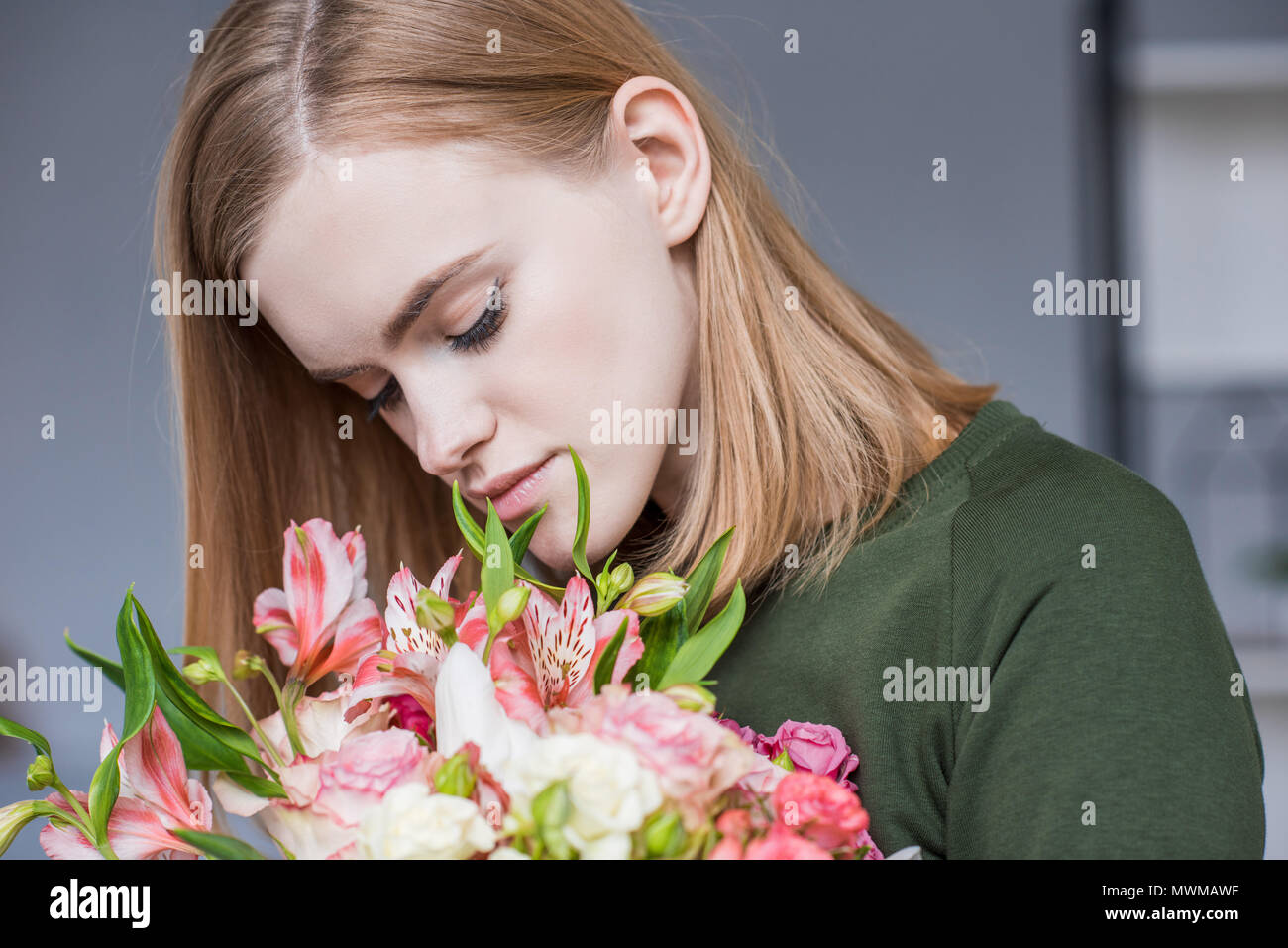 attractive young woman sniffing bouquet of flowers Stock Photo