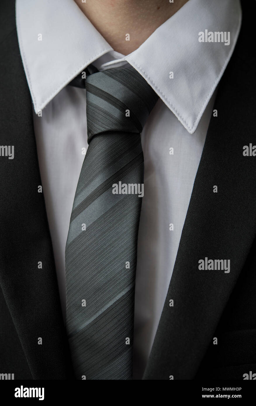 Close up of a smartly dressed teenager wearing a black suit, white shirt and black tie Stock Photo