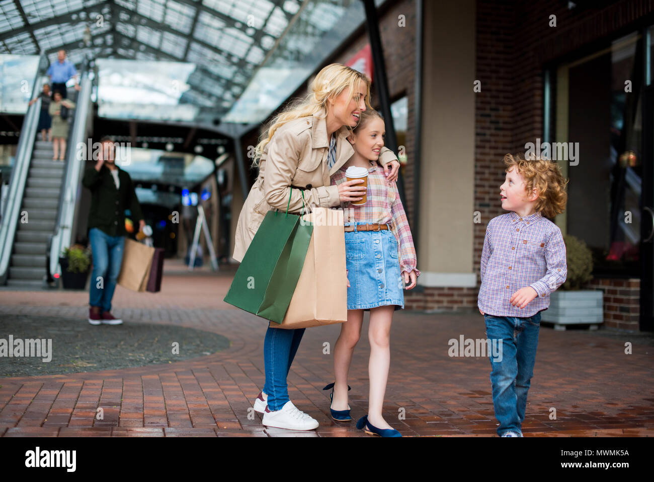 young mother talking with her little kids during shopping at shopping centre Stock Photo