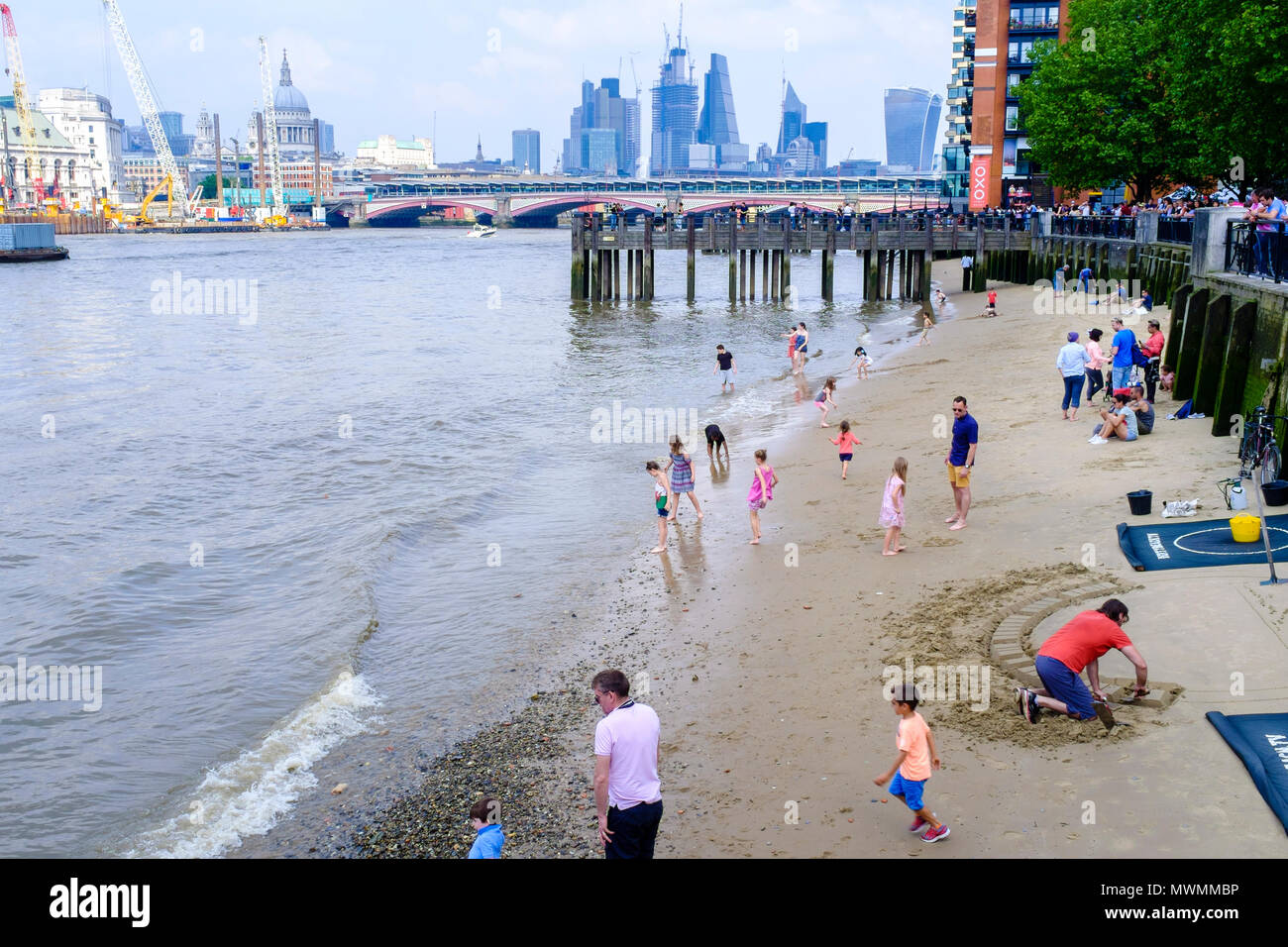 People enjoying the sandy beach of River Thames foreshore at low tide. Stock Photo