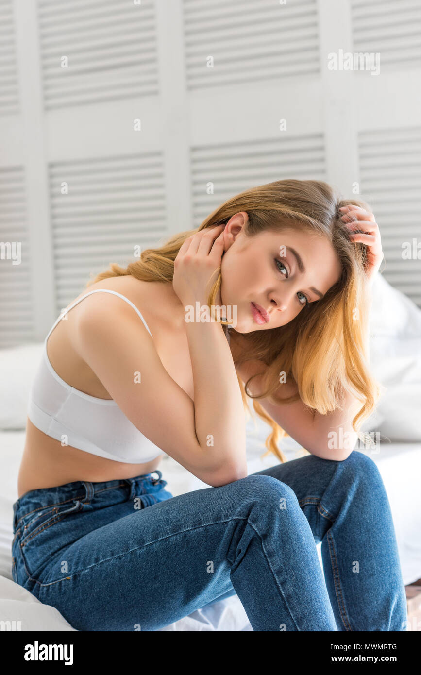 beautiful girl in jeans and white bra sitting on bed Stock Photo - Alamy